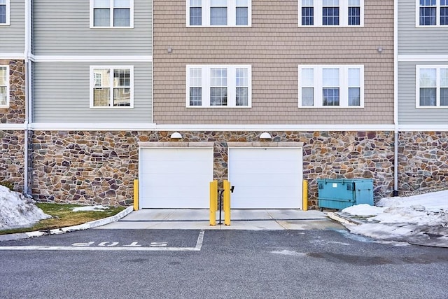 view of front facade with an attached garage, stone siding, and concrete driveway