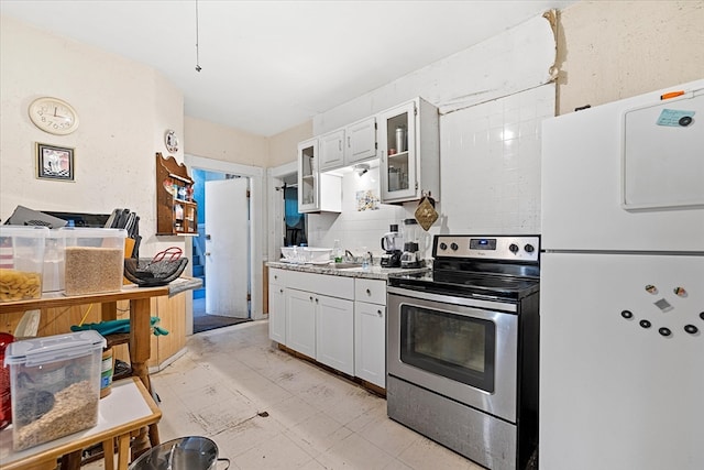 kitchen with stainless steel electric stove, white cabinetry, sink, and white refrigerator