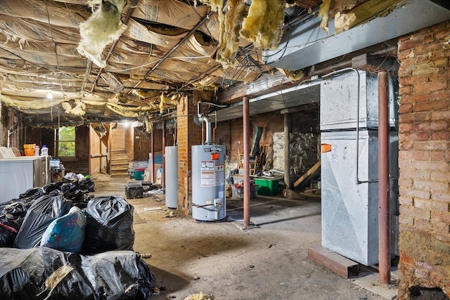 basement with brick wall, gas water heater, and washer and clothes dryer