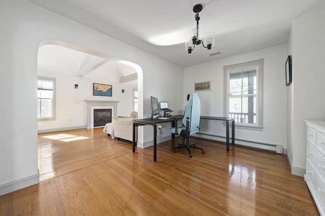 office space with wood finished floors, visible vents, a baseboard radiator, arched walkways, and a chandelier