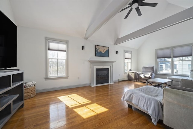 living room with wood finished floors, baseboards, a baseboard radiator, a fireplace with flush hearth, and ceiling fan