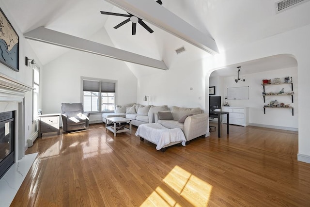 living area with visible vents, arched walkways, wood finished floors, and a ceiling fan