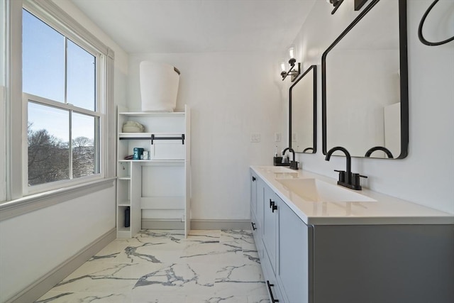 full bath featuring double vanity, marble finish floor, baseboards, and a sink