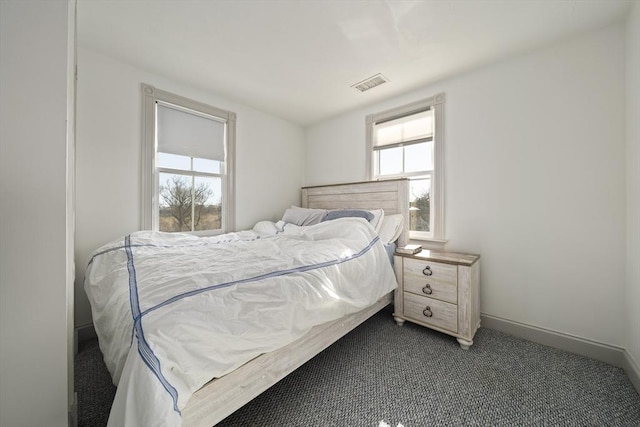 bedroom with baseboards, visible vents, and dark carpet