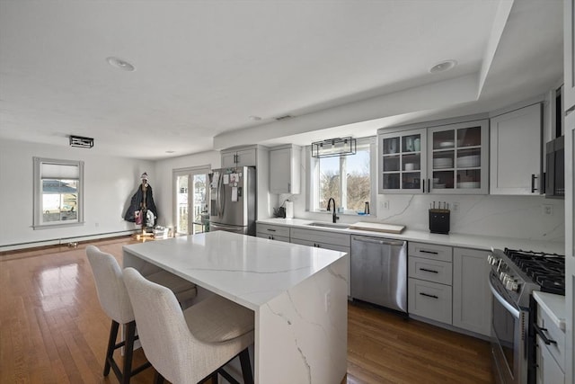 kitchen featuring gray cabinets, appliances with stainless steel finishes, a kitchen island, and a sink