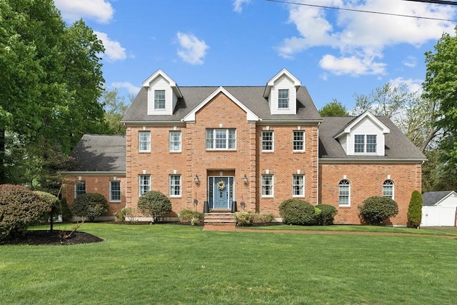 colonial house featuring brick siding and a front lawn