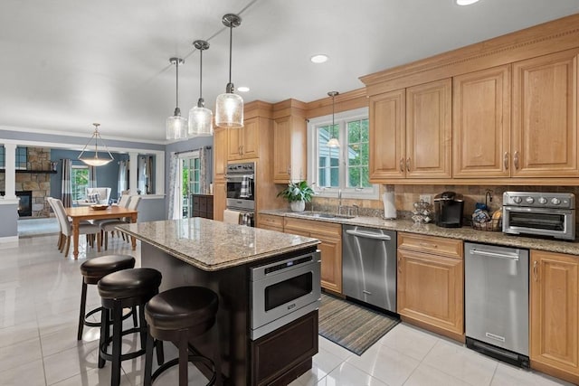 kitchen with stainless steel appliances, light stone counters, a sink, and recessed lighting