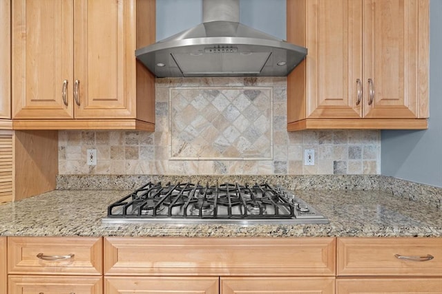 kitchen with exhaust hood, stainless steel gas stovetop, decorative backsplash, and light stone counters