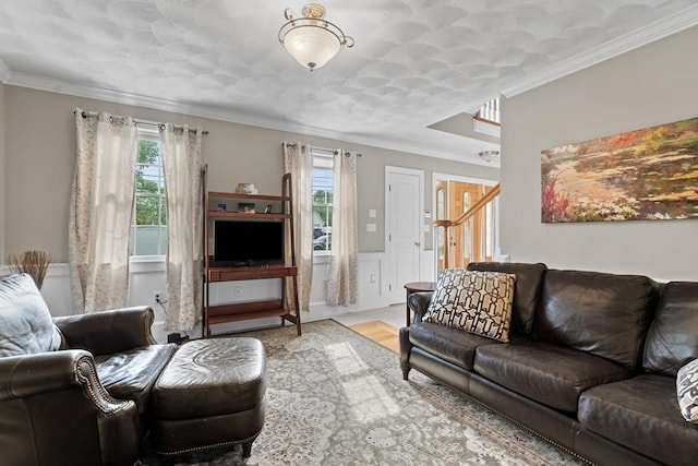 living room featuring plenty of natural light, ornamental molding, wood finished floors, and a wainscoted wall