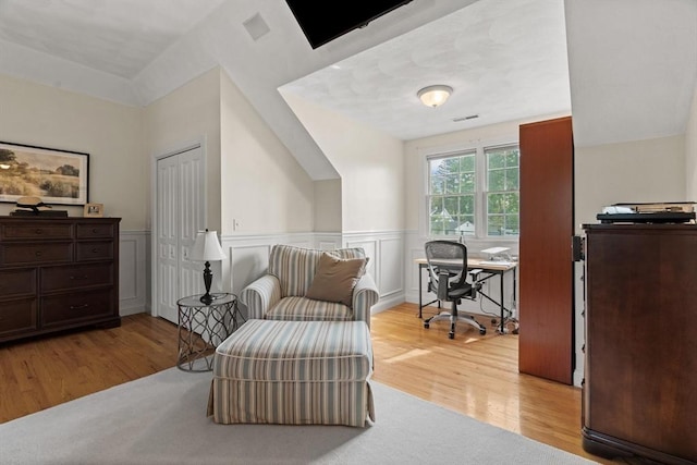 living area with light wood-style floors, a wainscoted wall, and an office area