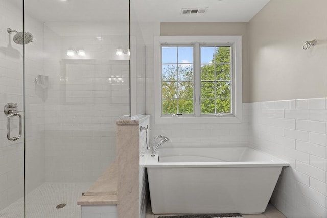 bathroom featuring a soaking tub, a stall shower, plenty of natural light, tile patterned floors, and tile walls