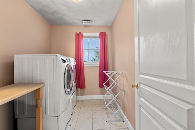 washroom featuring washer and dryer, baseboards, and light tile patterned floors