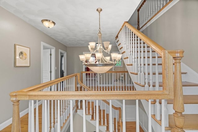 staircase featuring a chandelier, wood finished floors, and baseboards
