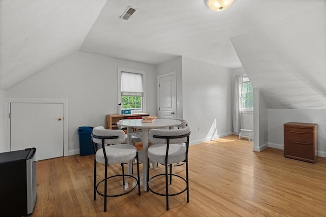 dining area featuring vaulted ceiling, light wood-style floors, healthy amount of natural light, and baseboards