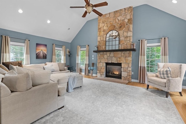 living room with a ceiling fan, wood finished floors, a stone fireplace, high vaulted ceiling, and recessed lighting