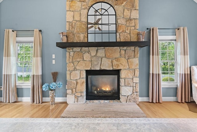detailed view of a fireplace, wood finished floors, and baseboards