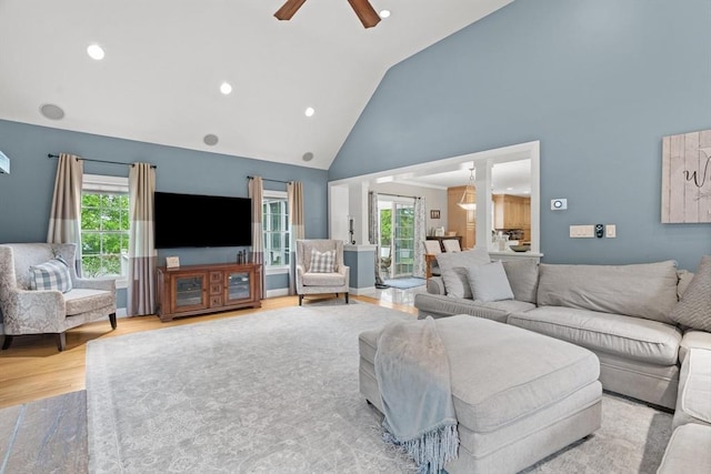 living area with high vaulted ceiling, ceiling fan, healthy amount of natural light, wood finished floors, and recessed lighting