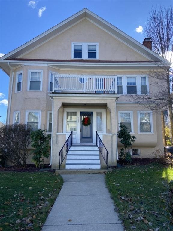 345 Ashmont St Unit 3, Boston, MA 02124 - view of front facade with a balcony, a chimney, stucco siding, and a front yard