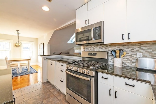 345 Ashmont St Unit 3, Boston, MA 02124 - kitchen with pendant lighting, white cabinetry, dark stone countertops, backsplash, and stainless steel appliances