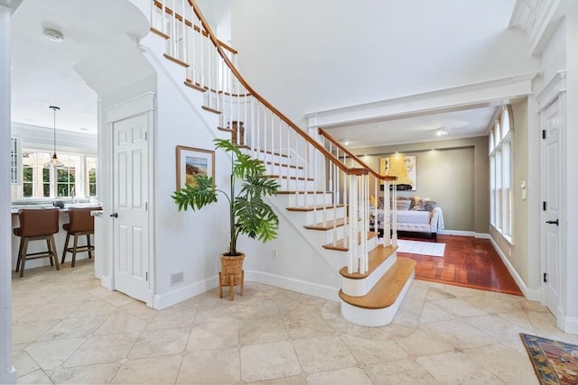 entrance foyer with crown molding, stairs, light tile patterned flooring, and baseboards