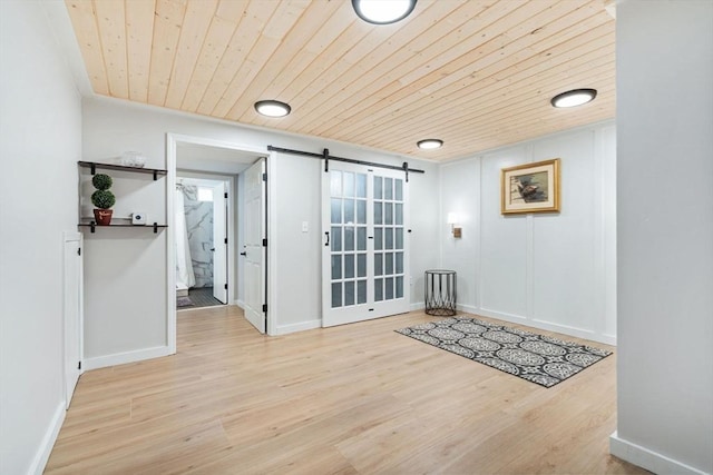doorway to outside featuring a barn door, wooden ceiling, wood finished floors, and baseboards