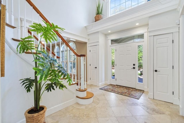 foyer featuring stairway, baseboards, and a towering ceiling