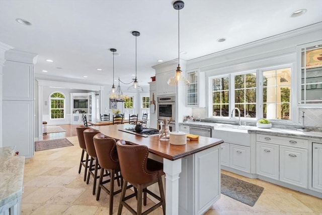 kitchen with stainless steel appliances, glass insert cabinets, a center island, crown molding, and a sink