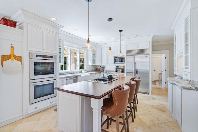 kitchen with built in appliances, white cabinetry, ornamental molding, backsplash, and decorative light fixtures
