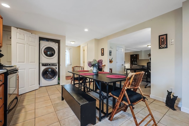 tiled dining space featuring stacked washer and clothes dryer