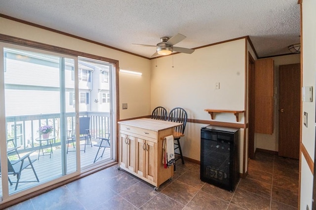 kitchen featuring wine cooler, a textured ceiling, crown molding, and a healthy amount of sunlight