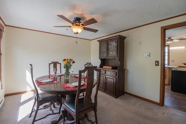 dining room with a ceiling fan, a textured ceiling, baseboards, light carpet, and ornamental molding