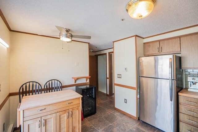 kitchen featuring freestanding refrigerator, a textured ceiling, ornamental molding, ceiling fan, and baseboards