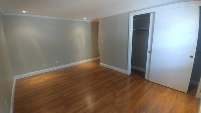 unfurnished bedroom featuring a closet, hardwood / wood-style floors, and ornamental molding