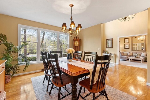 dining space with a chandelier, light wood-style flooring, and baseboards