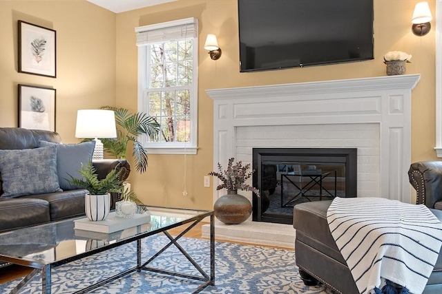 living room with a brick fireplace and wood finished floors