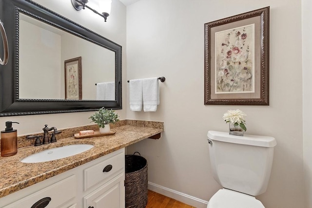 bathroom with baseboards, toilet, wood finished floors, and vanity