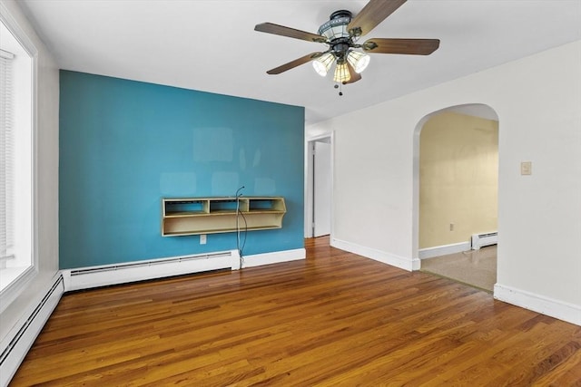 7 Burgess St, Methuen, MA 01844 - empty room with baseboard heating, arched walkways, ceiling fan, and wood finished floors