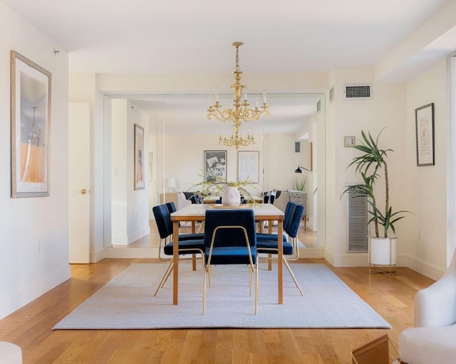 dining area featuring an inviting chandelier and light hardwood / wood-style flooring