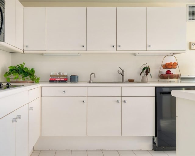 kitchen featuring sink, light tile patterned floors, black dishwasher, cooktop, and white cabinets