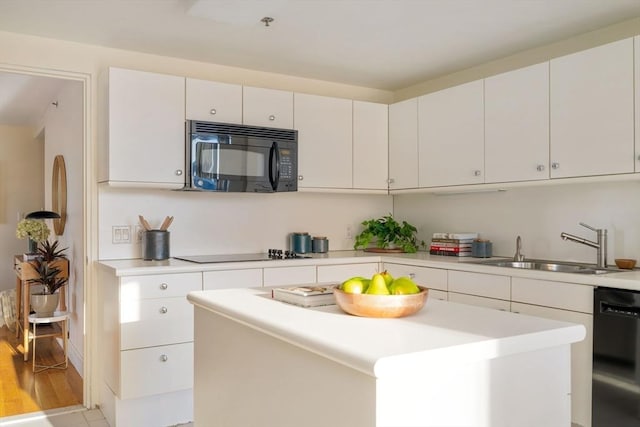 kitchen with white cabinetry, sink, a center island, light hardwood / wood-style flooring, and black appliances