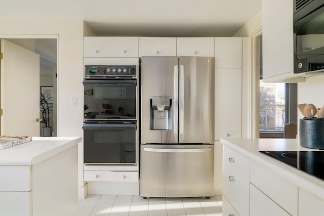 kitchen with light tile patterned flooring, white cabinets, and black appliances