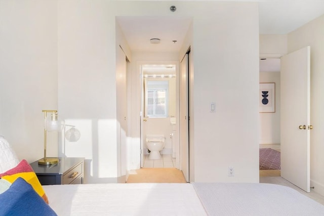 bedroom with light tile patterned floors and ensuite bath