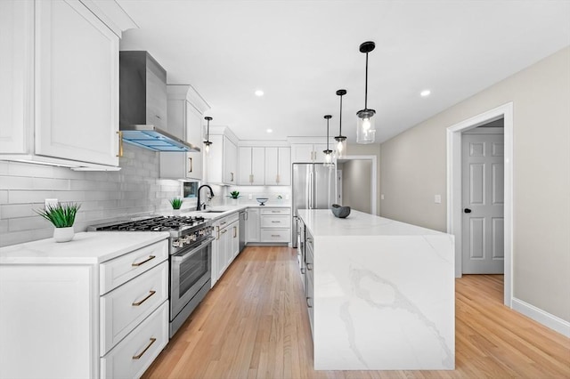 46 Mansfield Ave, Norton, MA 02766 - kitchen with light wood-style flooring, decorative backsplash, appliances with stainless steel finishes, wall chimney range hood, and a center island