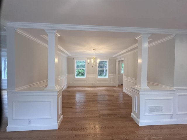 58 Dudley Rd, Billerica, MA 01821 - unfurnished dining area with a decorative wall, a chandelier, crown molding, wood finished floors, and ornate columns