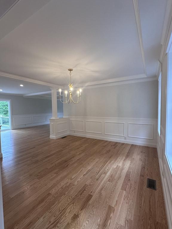 58 Dudley Rd, Billerica, MA 01821 - unfurnished dining area with a decorative wall, a chandelier, wood finished floors, crown molding, and wainscoting