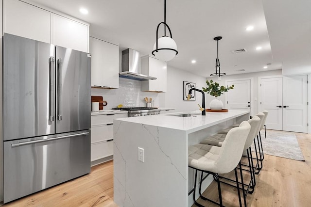 190 Salem St Unit 2, Boston, MA 02113 - kitchen featuring high end fridge, a sink, wall chimney range hood, a kitchen breakfast bar, and white cabinetry