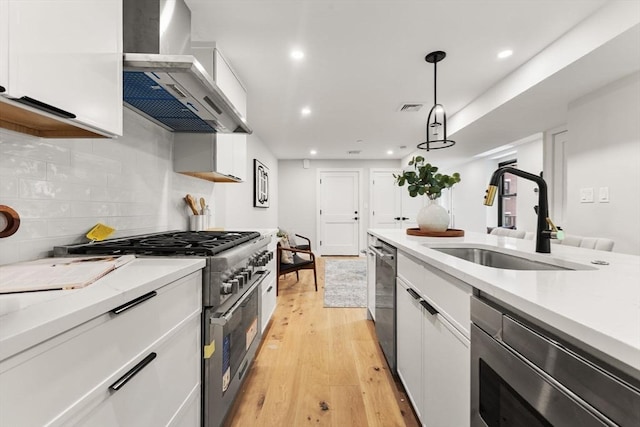 190 Salem St Unit 2, Boston, MA 02113 - kitchen with wall chimney range hood, stainless steel appliances, a sink, white cabinets, and light wood-style floors