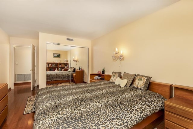 bedroom with dark wood-style floors, visible vents, and a closet