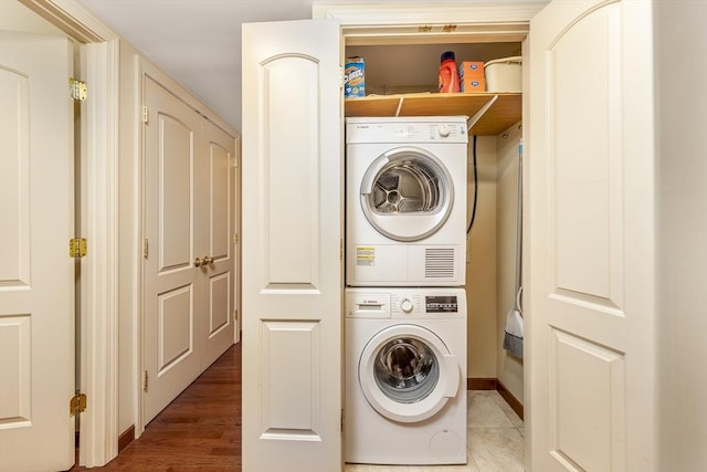 laundry room featuring laundry area, wood finished floors, and stacked washer and clothes dryer