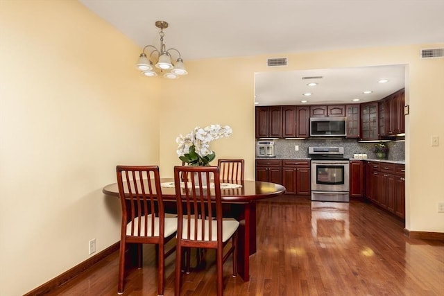 kitchen with stainless steel appliances, visible vents, dark wood-style floors, and tasteful backsplash